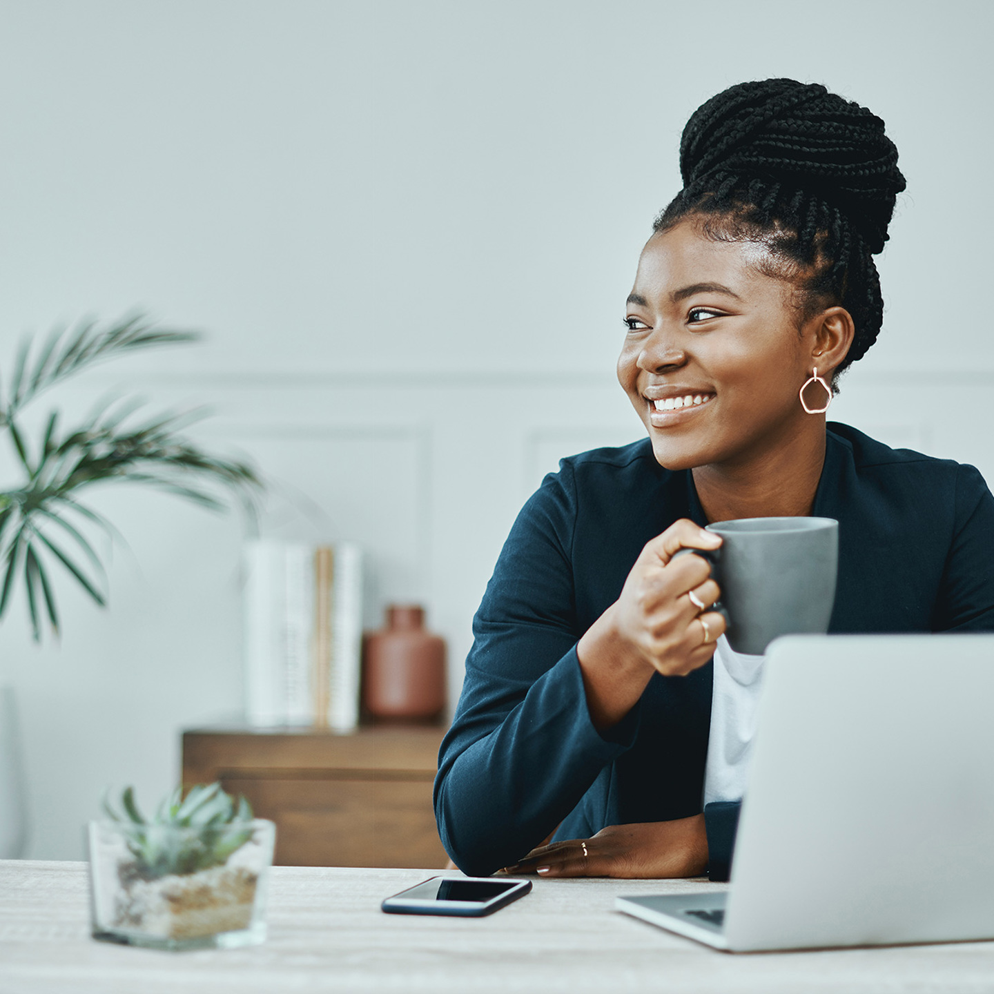 Young female with an open laptop drinking coffee