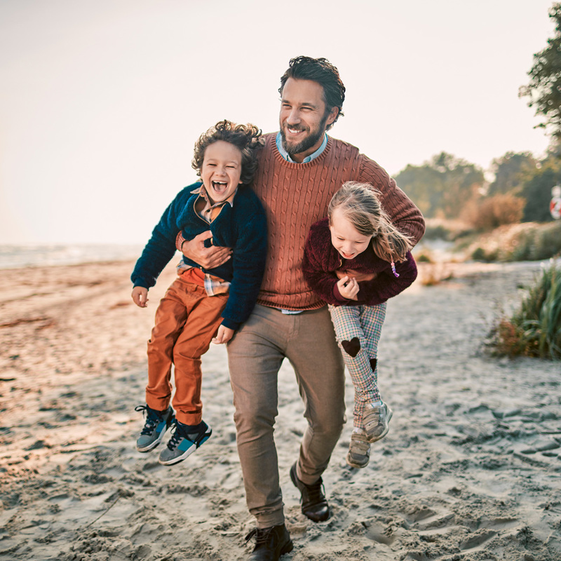 Young father with his two young children on a beach