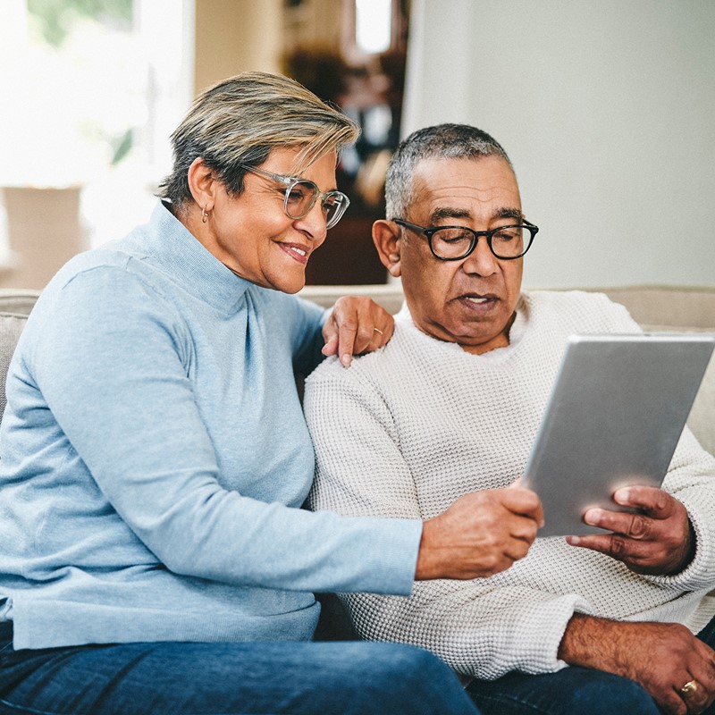 Man and woman sitting on couch looking at an iPad